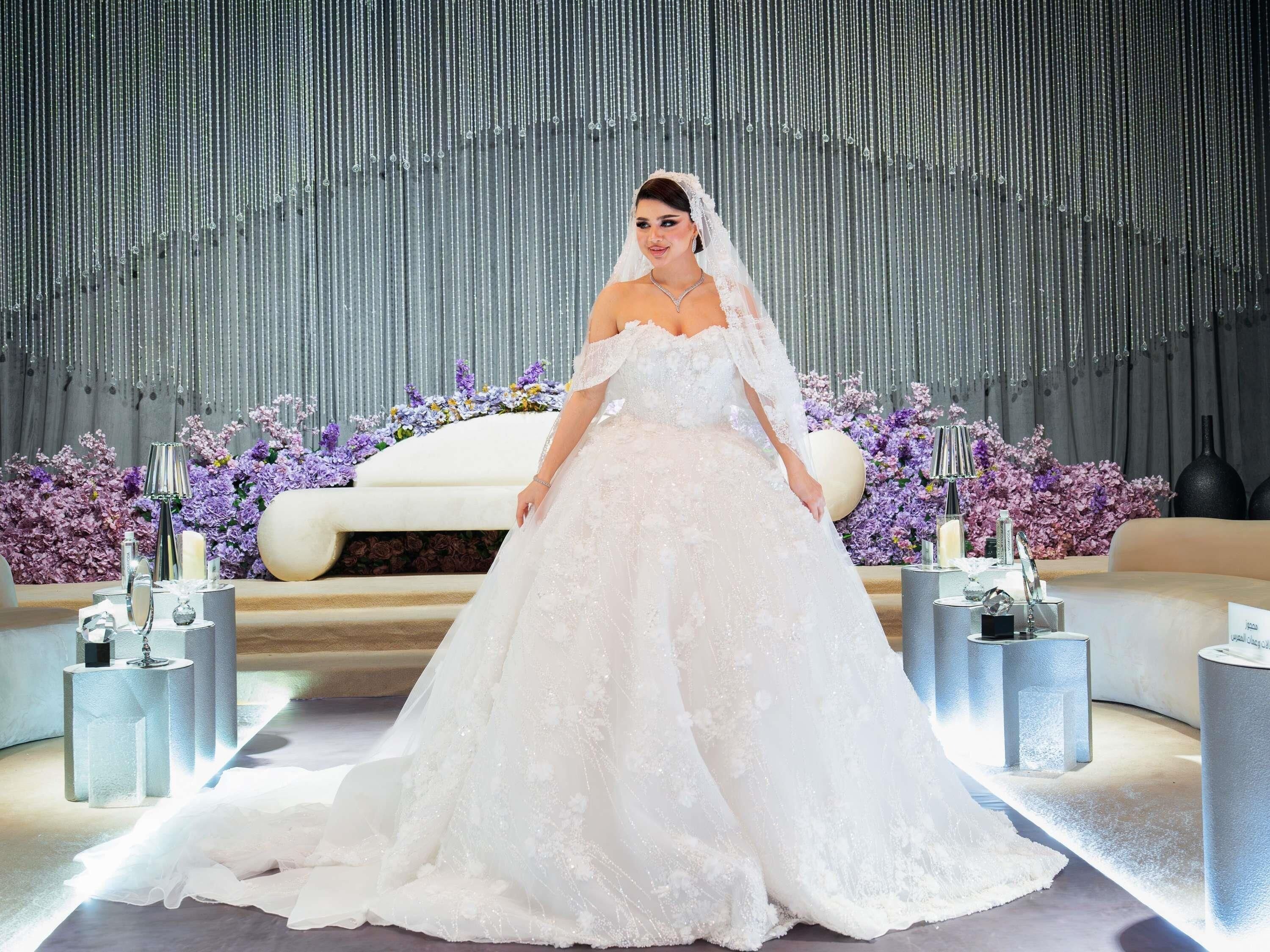 Une robe de mariée dans un cadre luxueux, avec un décor réfléchissant et des arrangements floraux.