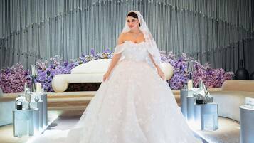 Une robe de mariée dans un cadre luxueux, avec un décor réfléchissant et des arrangements floraux.