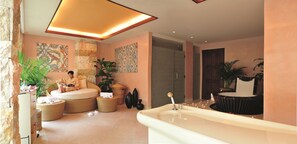 Un baño moderno con una bañera grande, una zona de estar con una persona leyendo y decoración artística en la pared.