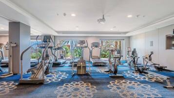 A hotel gym with treadmills, ellipticals, and a ceiling fan.