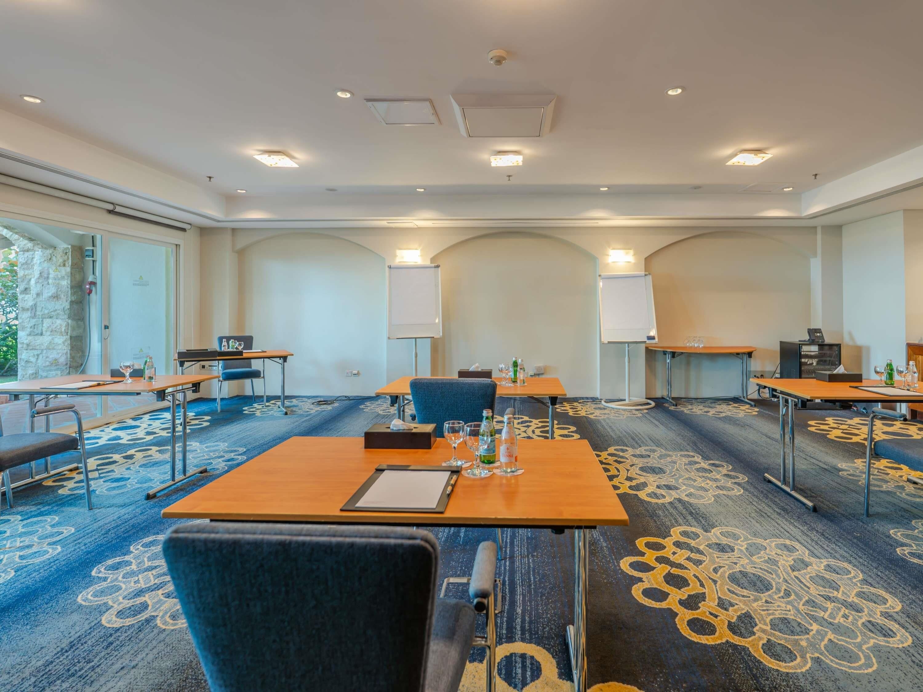 A conference room with tables, chairs, whiteboards, and a carpeted floor.