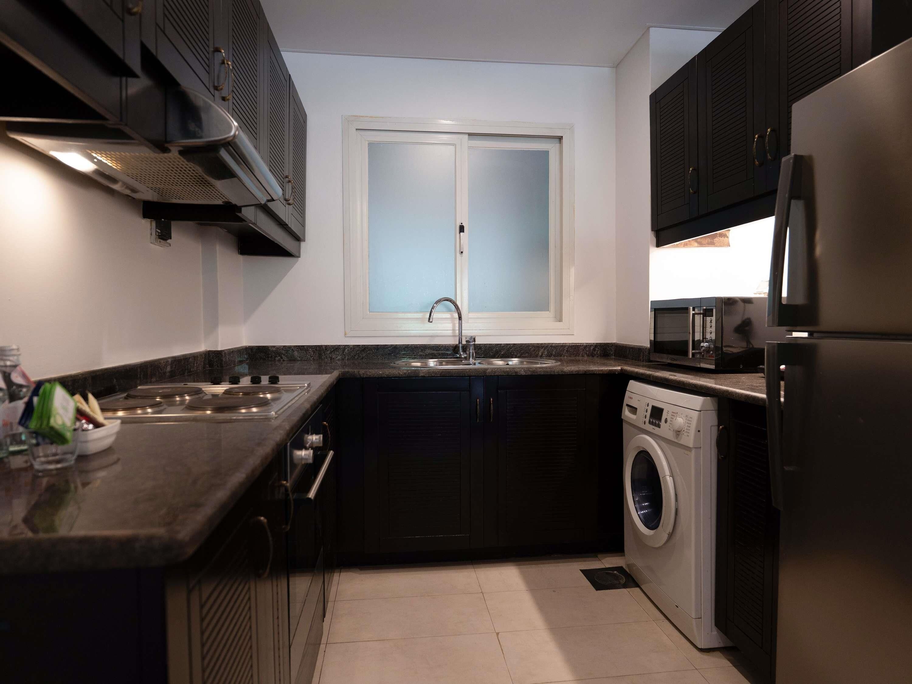 A compact kitchen with a built-in oven, microwave, and washing machine.