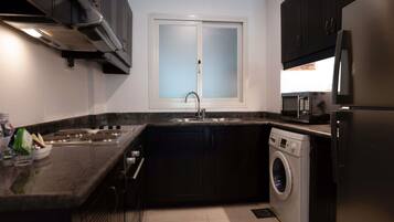 A compact kitchen with a built-in oven, microwave, and washing machine.