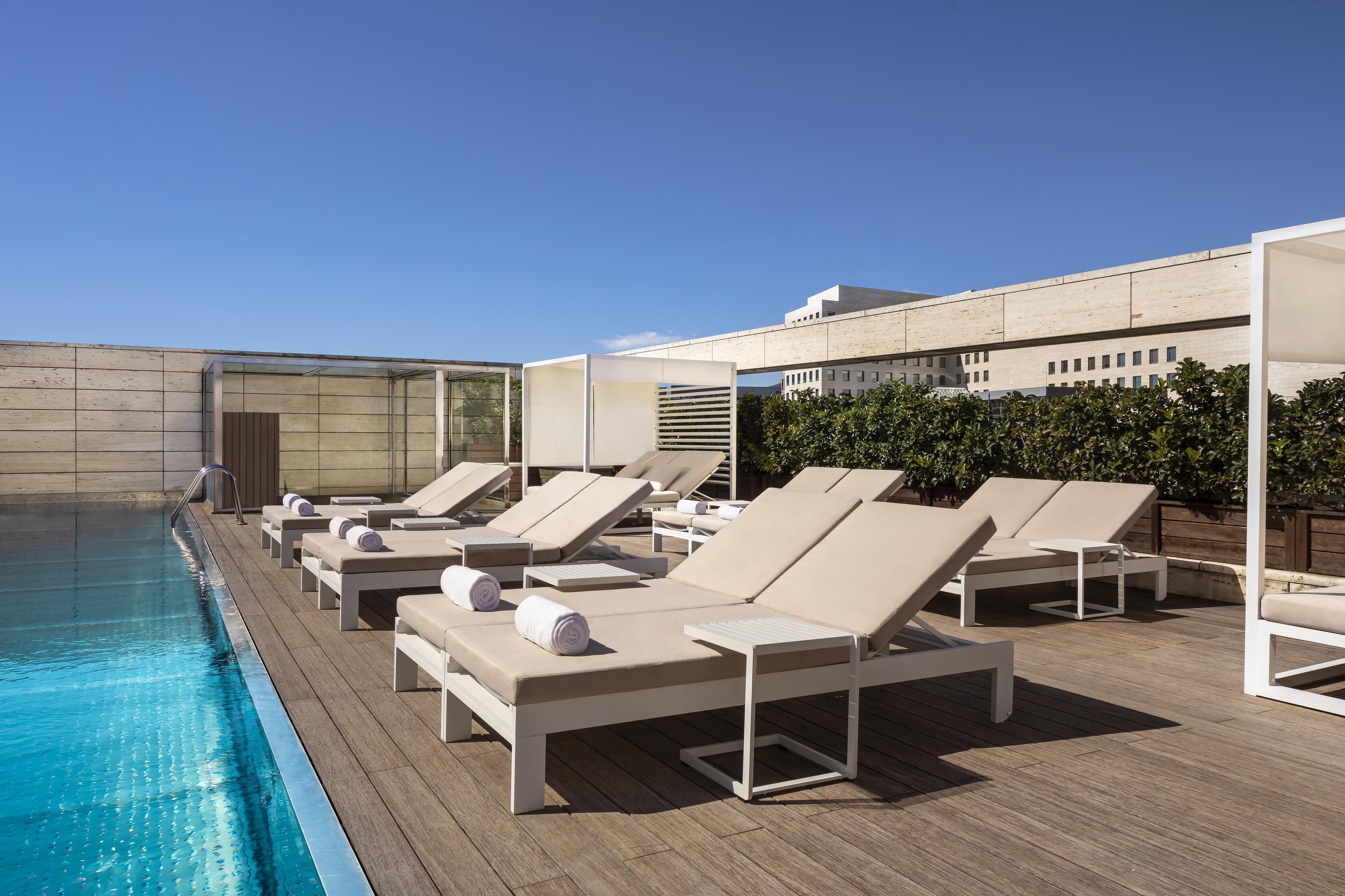Una piscina al aire libre, sillones reclinables de piscina