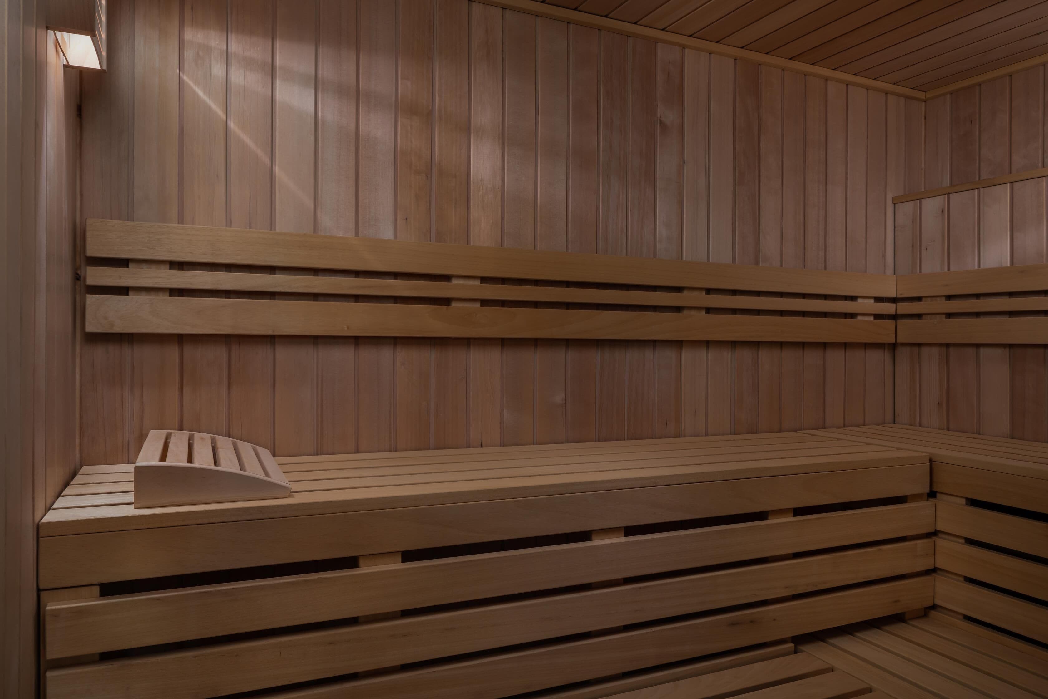 Una sauna con bancos de madera y un banco con respaldo.