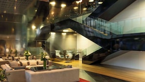 Un interior moderno con una zona de estar central, una escalera de cristal y vistas al exterior.