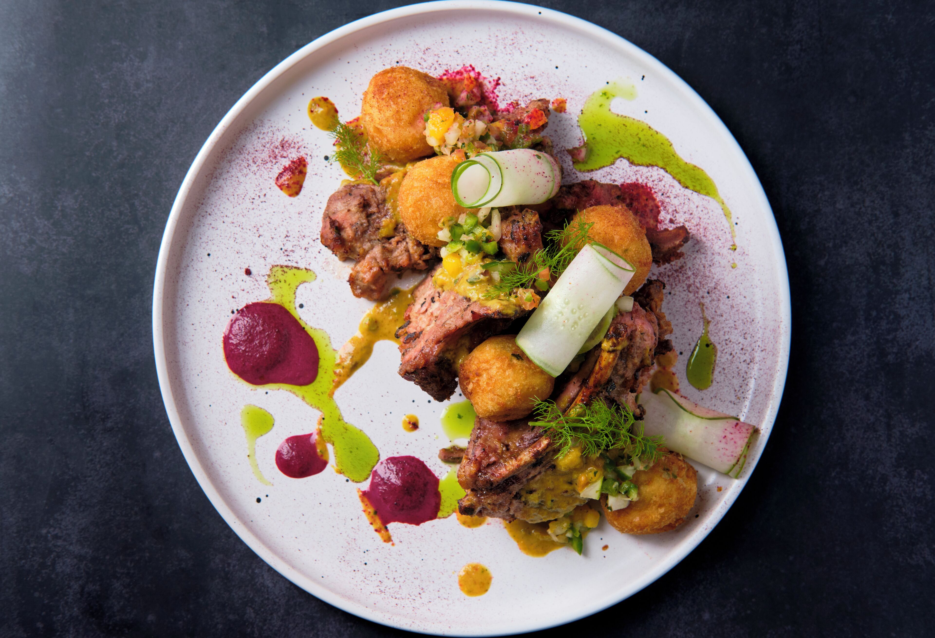 Un plato de comida con carne, verduras y salsas.