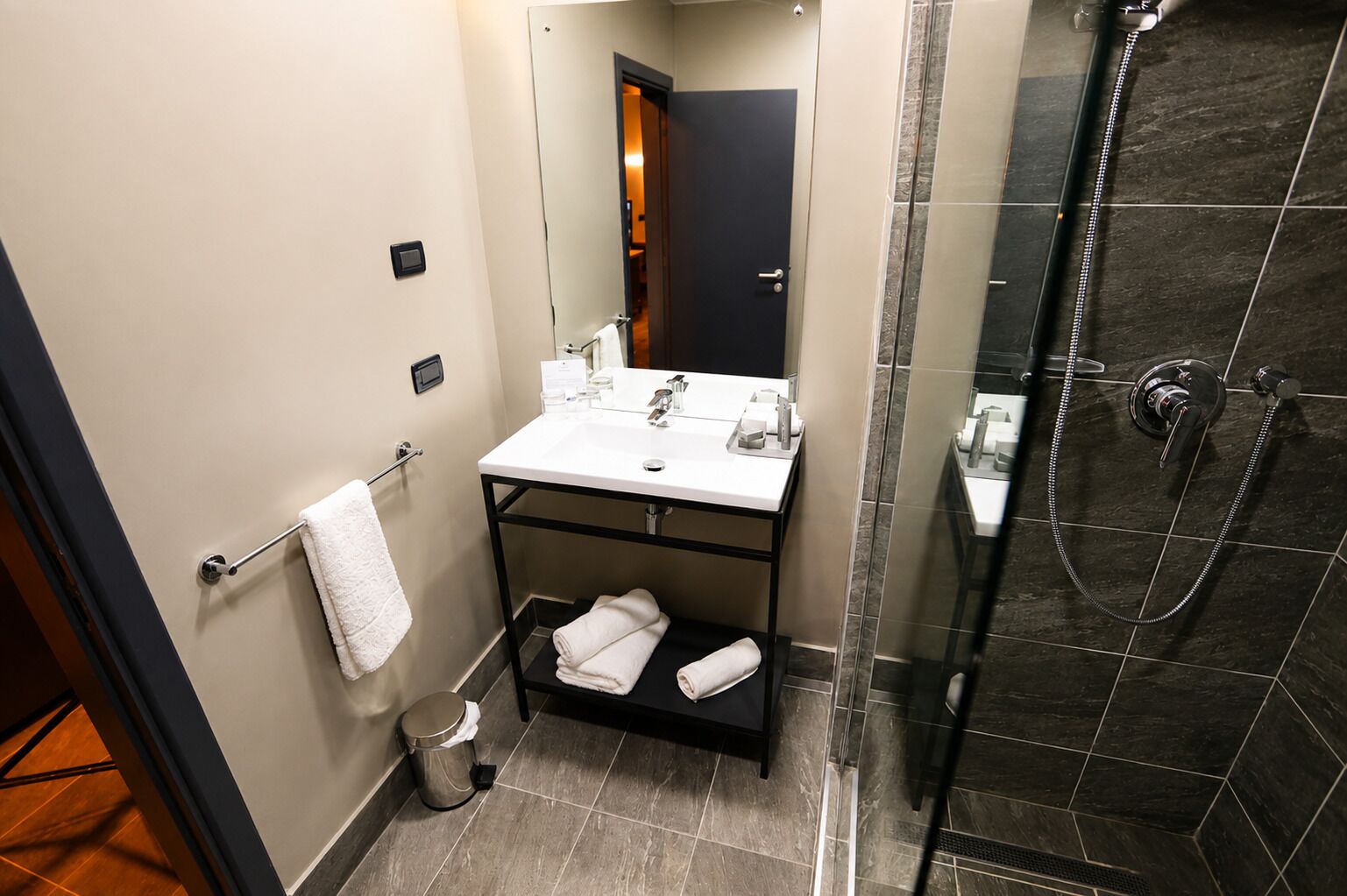 A modern bathroom with a shower, a sink, and a mirror.