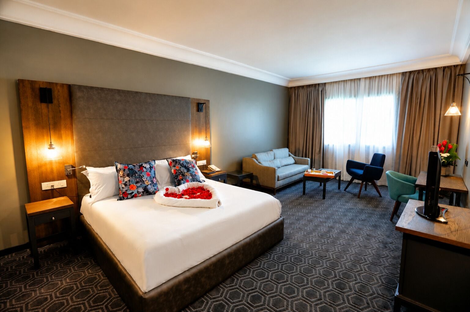 A hotel room with a large bed, a sofa, a desk, and a chair.