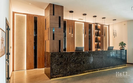 A modern reception area with a marble counter, wooden paneling, and pendant lighting.