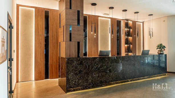 A modern reception area with a marble counter, wooden paneling, and pendant lighting. - Fiesta Royale Hotel (Accra)