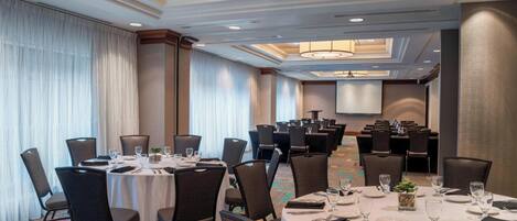 A conference room with round tables, chairs, and a large screen.