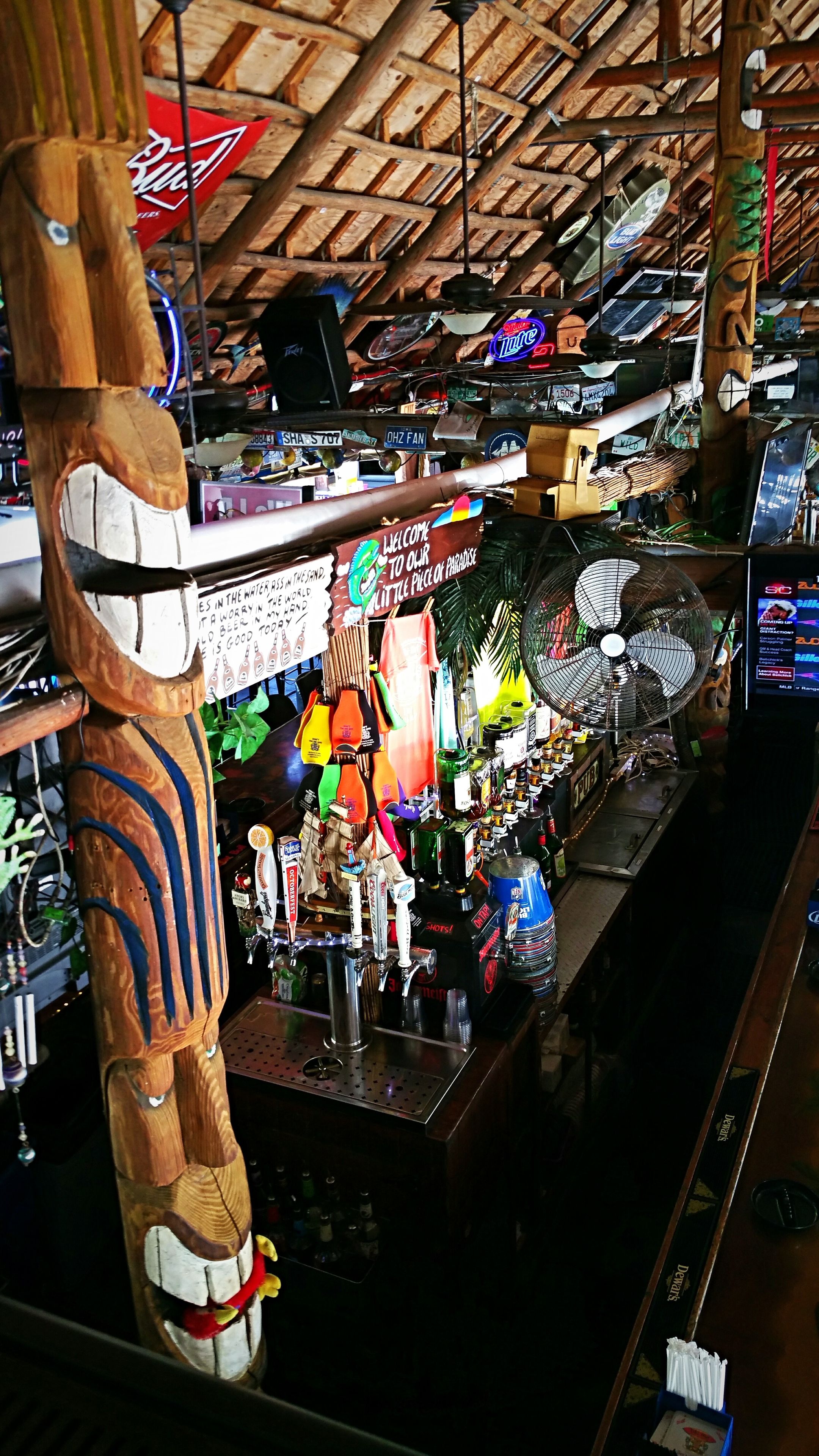 Una zona de bar con techo de madera, varios letreros y una escultura de madera.