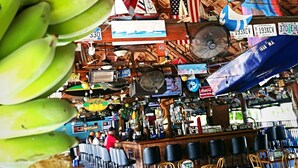 A restaurant with a high wooden ceiling, hanging flags, and a variety of flags and decorations. - Dolphin Key Resort (Cape Coral)