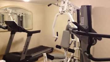 Una palestra in casa con tapis roulant, panca per pesi e diverse macchine per esercizi.