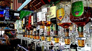A bar with multiple liquor bottles and a large American flag in the background. - Dolphin Key Resort (Cape Coral)