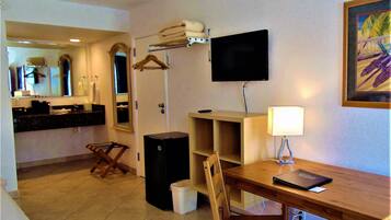 Une chambre d’hôtel avec un lit, un bureau et une chaise, une télévision, une lampe et un tableau au mur.
