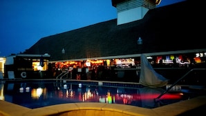 A nighttime view of a bar with a pool in front. - Dolphin Key Resort (Cape Coral)