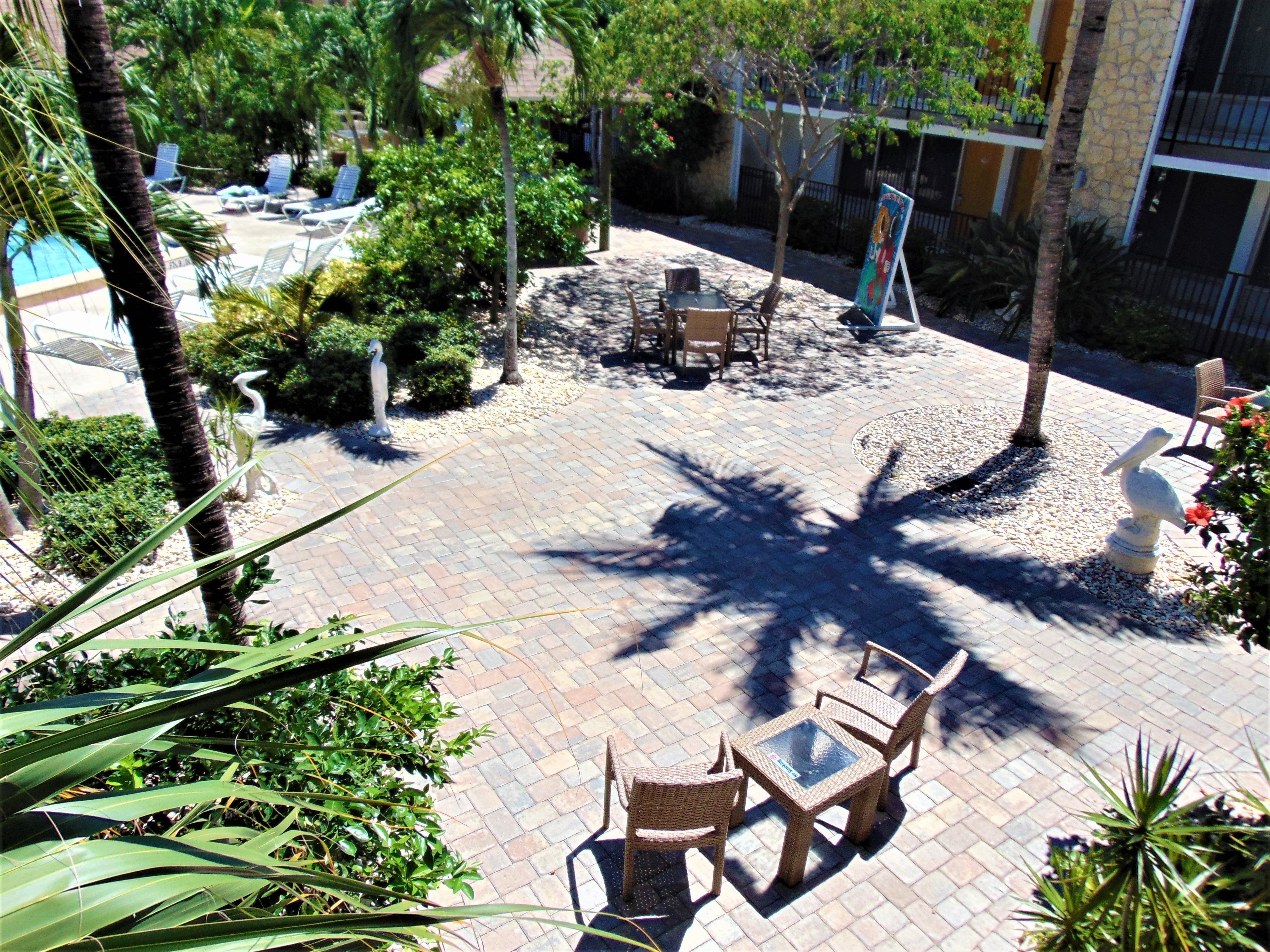 A patio area with wicker furniture, a statue, and a pool in the background.