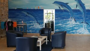 A lobby with a mural of dolphins, seating area, and a reception desk. - Dolphin Key Resort (Cape Coral)