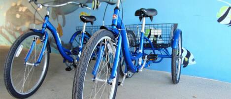 Ein blaues Fahrrad mit Korb und Gepäckträger, abgebestellt in einem Raum an einer blauen Wand.