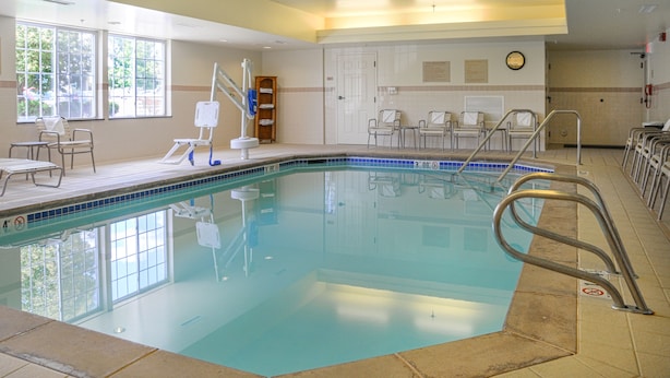 A swimming pool with a tiled deck, a lifeguard stand, and several lounge chairs.