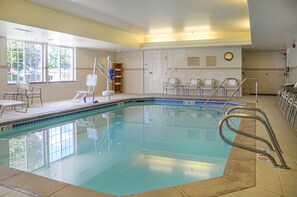 A swimming pool with a tiled deck, a lifeguard stand, and several lounge chairs. - TownePlace Suites Colorado Springs South (Colorado Springs)