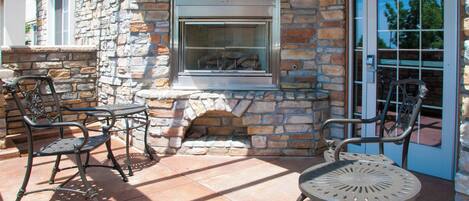 A patio with stone walls, metal chairs, and a table.