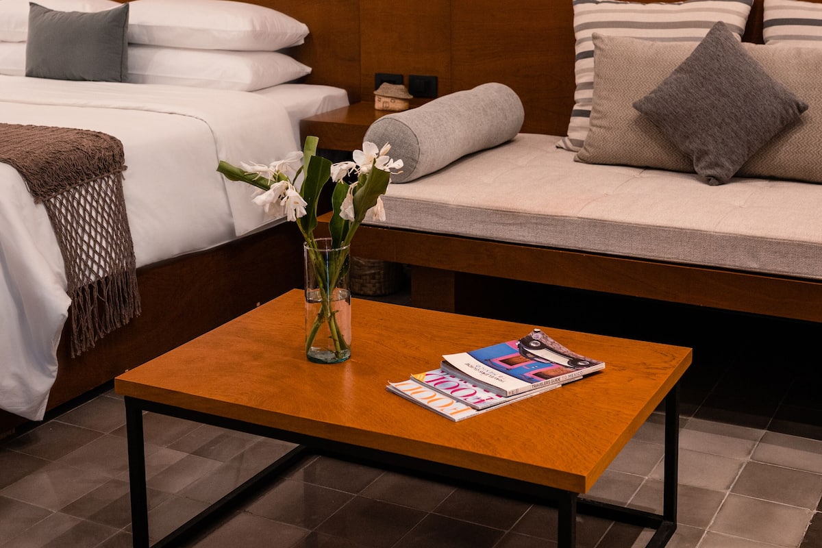 A hotel room with a bed, a sofa, a coffee table, and a wall art piece.