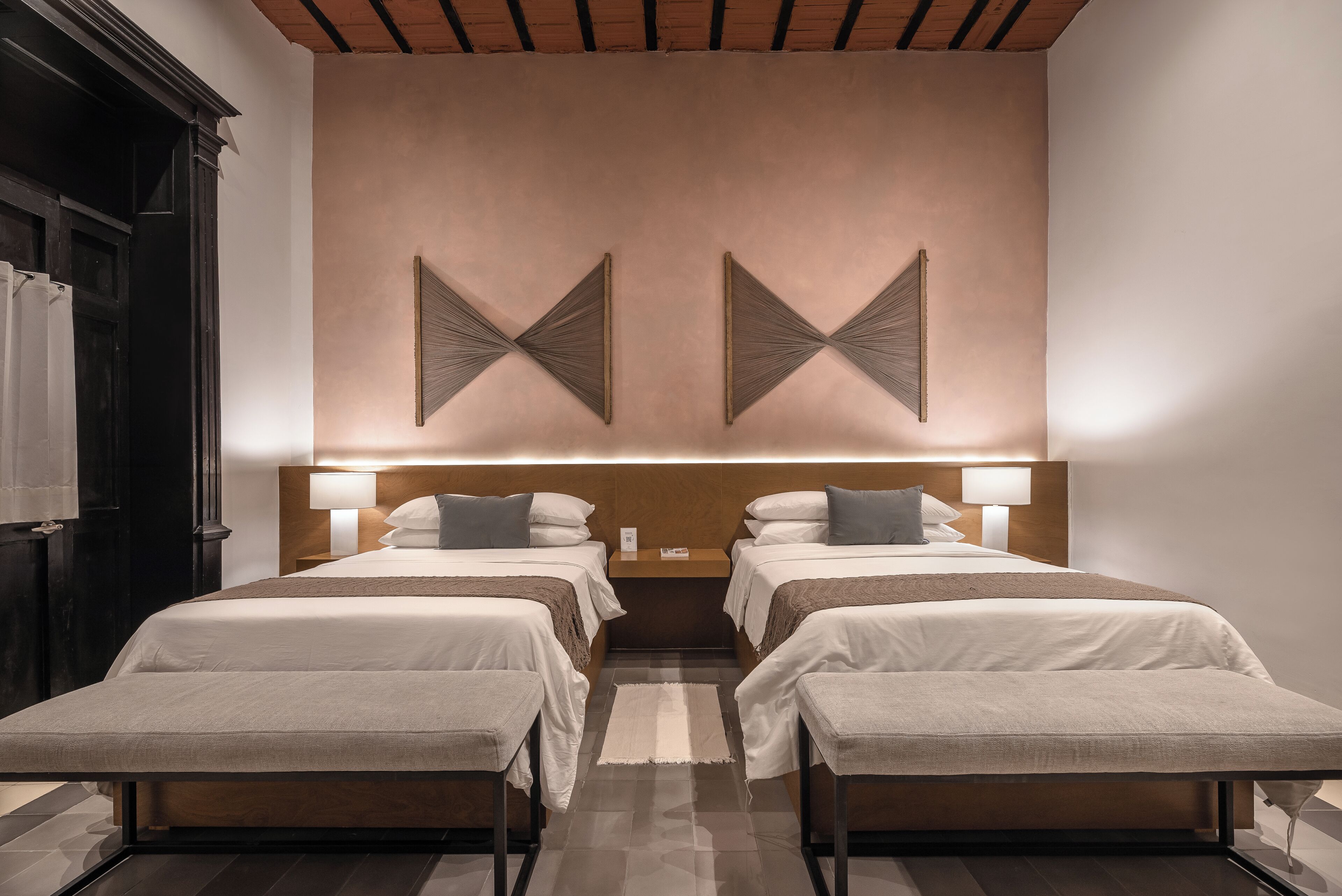 Habitación de hotel con dos camas, techo de madera y una gran obra de arte en la pared.