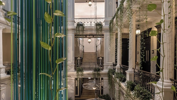 A spacious atrium with a central circular seating area, high ceilings with skylights, and vertical greenery.