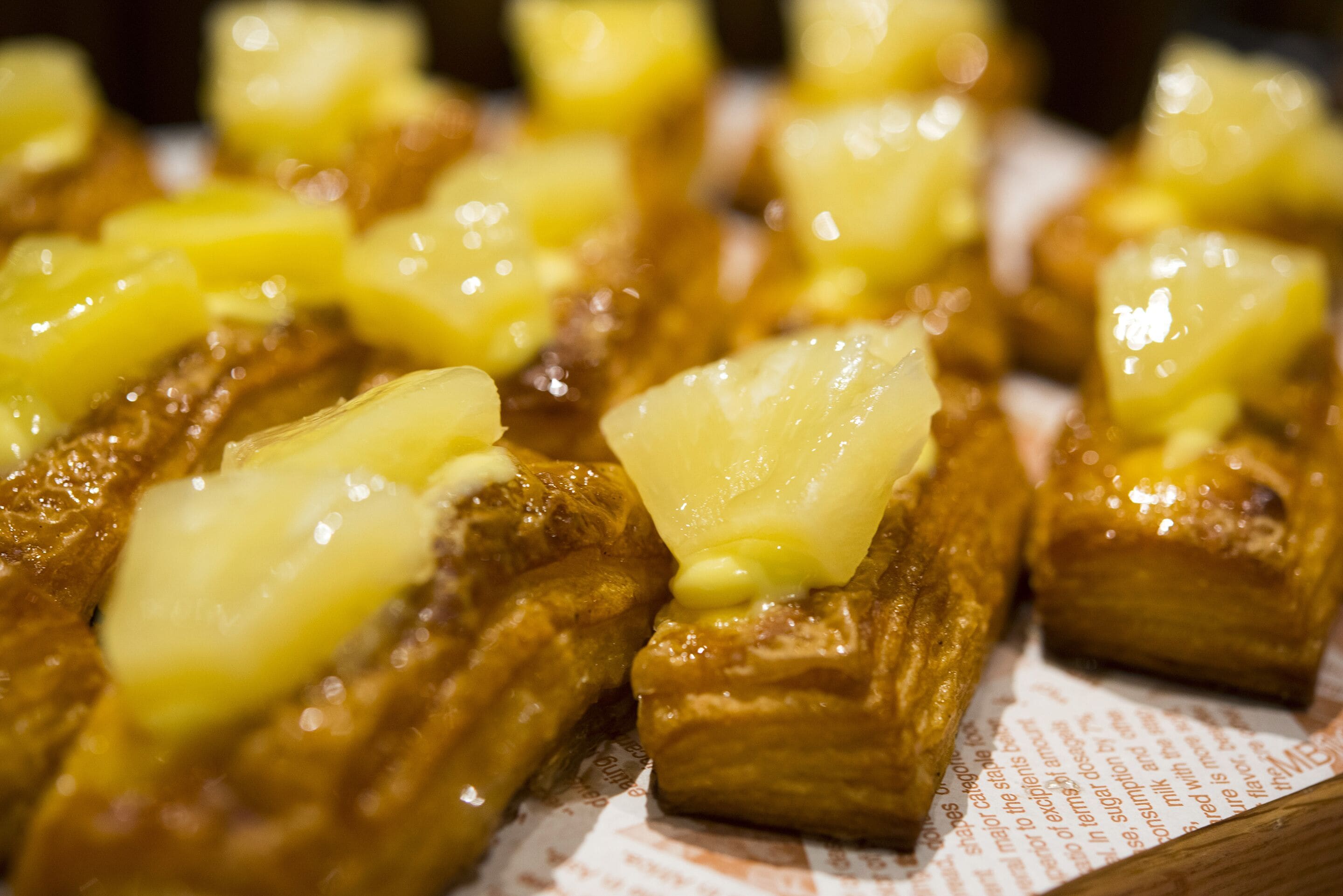 Primer plano de un postre con trozos de piña encima.