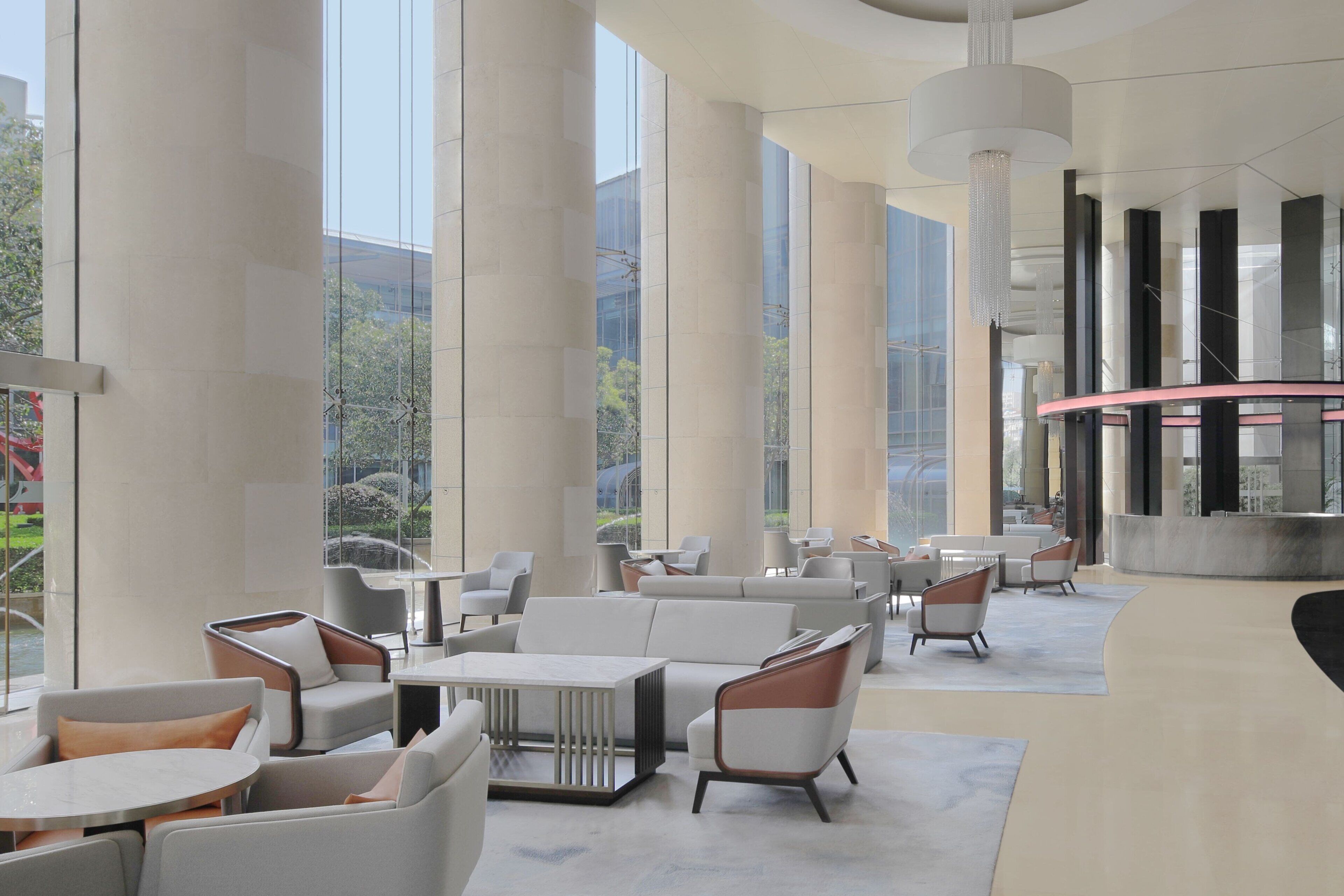 A spacious lobby with high ceilings, large windows, and modern furniture.