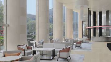 A spacious lobby with high ceilings, large windows, and modern furniture.