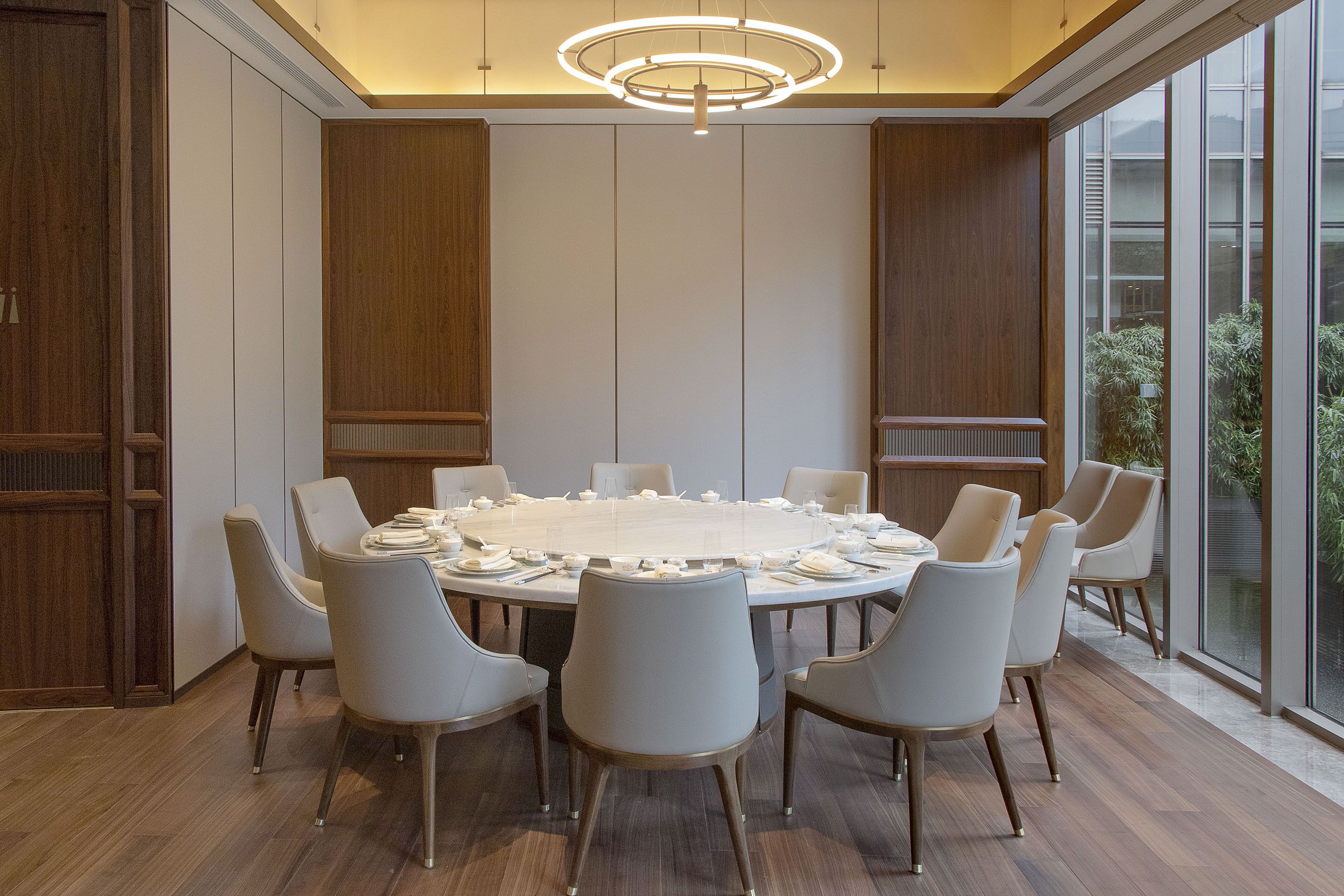 Une salle de conférence moderne dotée d’une table ronde, de chaises blanches et d’un luminaire au plafond au design original.