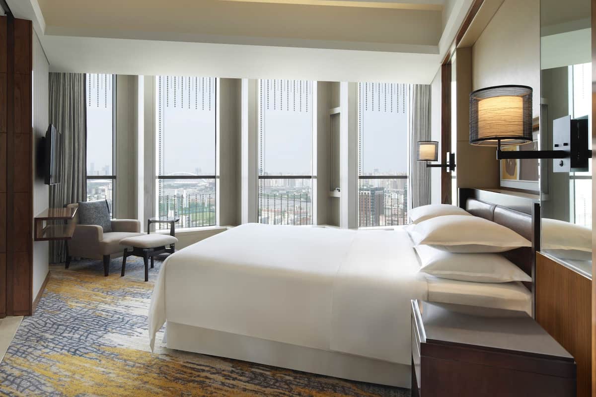 A hotel room with a large bed, a desk, a chair, and a TV.