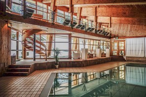 Un amplio espacio interior con una escalera de caracol, ventanas grandes y una piscina reflectante.