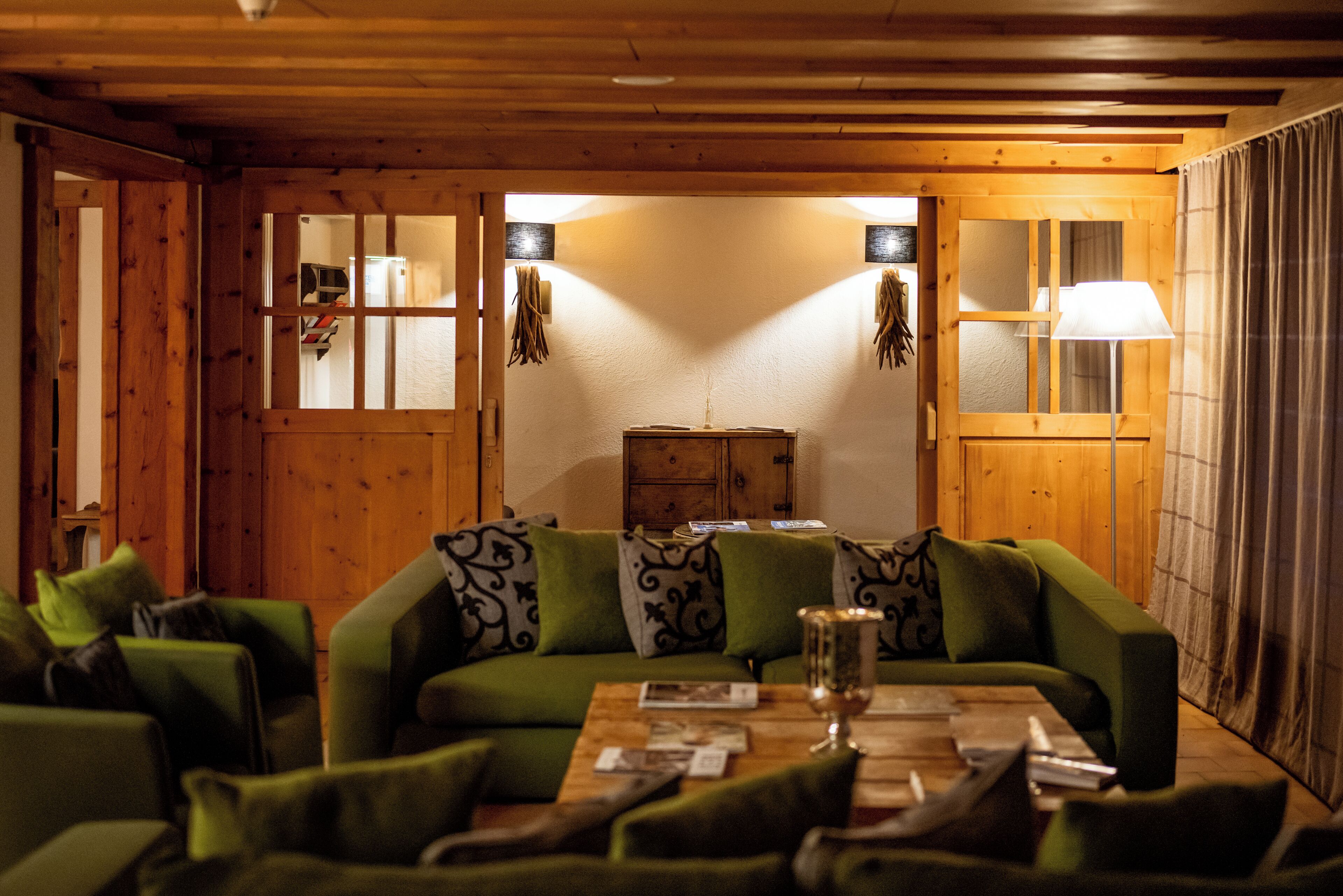 A cozy room with a green sofa, wooden walls, and a wooden cabinet.