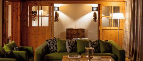 A cozy room with a green sofa, wooden walls, and a wooden cabinet.