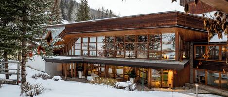A modern wooden building with large windows and a covered outdoor area.