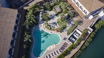 Relax by the central pool surrounded by lush greenery and palm trees, accessible via a paved walkway.