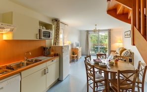 A compact kitchen with a microwave, sink, and a small dining area with a table and chairs. - Résidence Lagrange Vacances Les Roches Douvres (Saint-Briac-sur-Mer)