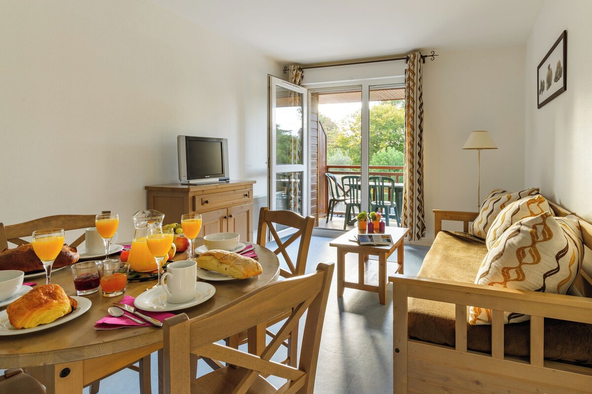 A dining area with a table set for breakfast, including croissants, juice, and a television on a cabinet.
