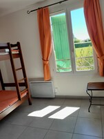 Una habitación con literas, un escritorio, una ventana con cortinas y un radiador.