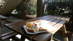 A wooden picnic table with a tray containing a glass of orange juice, a cup, and two slices of bread. - Premiere Classe Montpellier Sud - Lattes (Lattes)