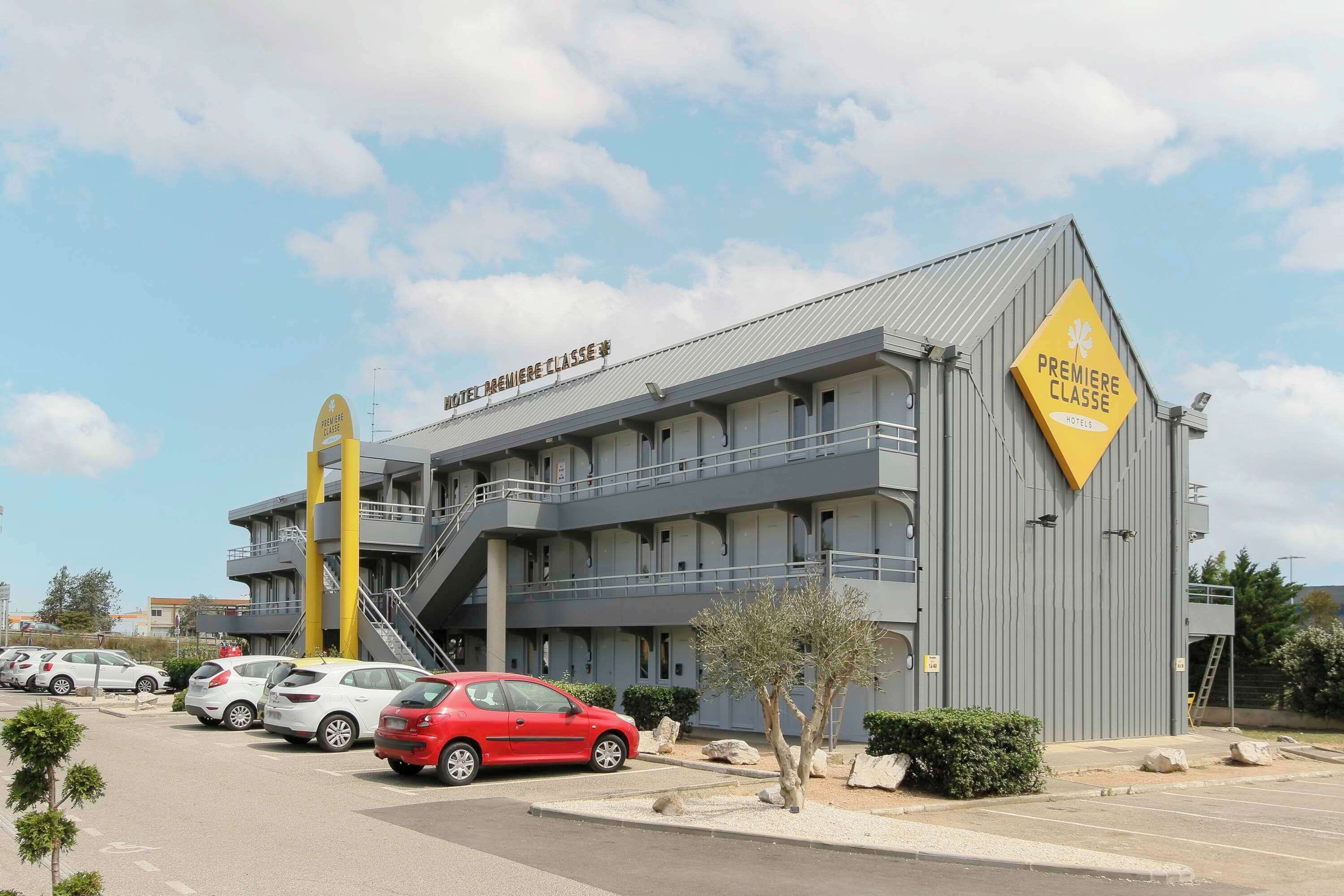 A hotel with a modern design, featuring a prominent yellow sign and multiple balconies.