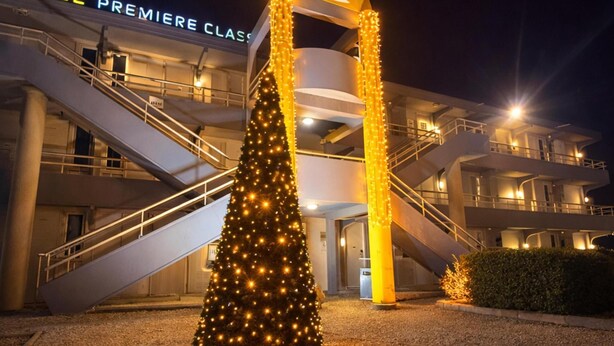 A hotel entrance with a Christmas tree and a sign reading "Premiere Classe".