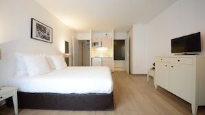 Une chambre d’hôtel équipée d’un lit, d’une télévision, d’un bureau et d’une kitchenette.