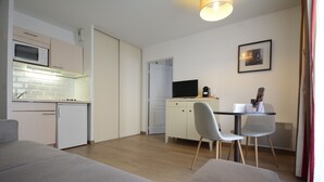 Un espace de vie compact comprenant un coin cuisine, un coin repas et un coin salon.