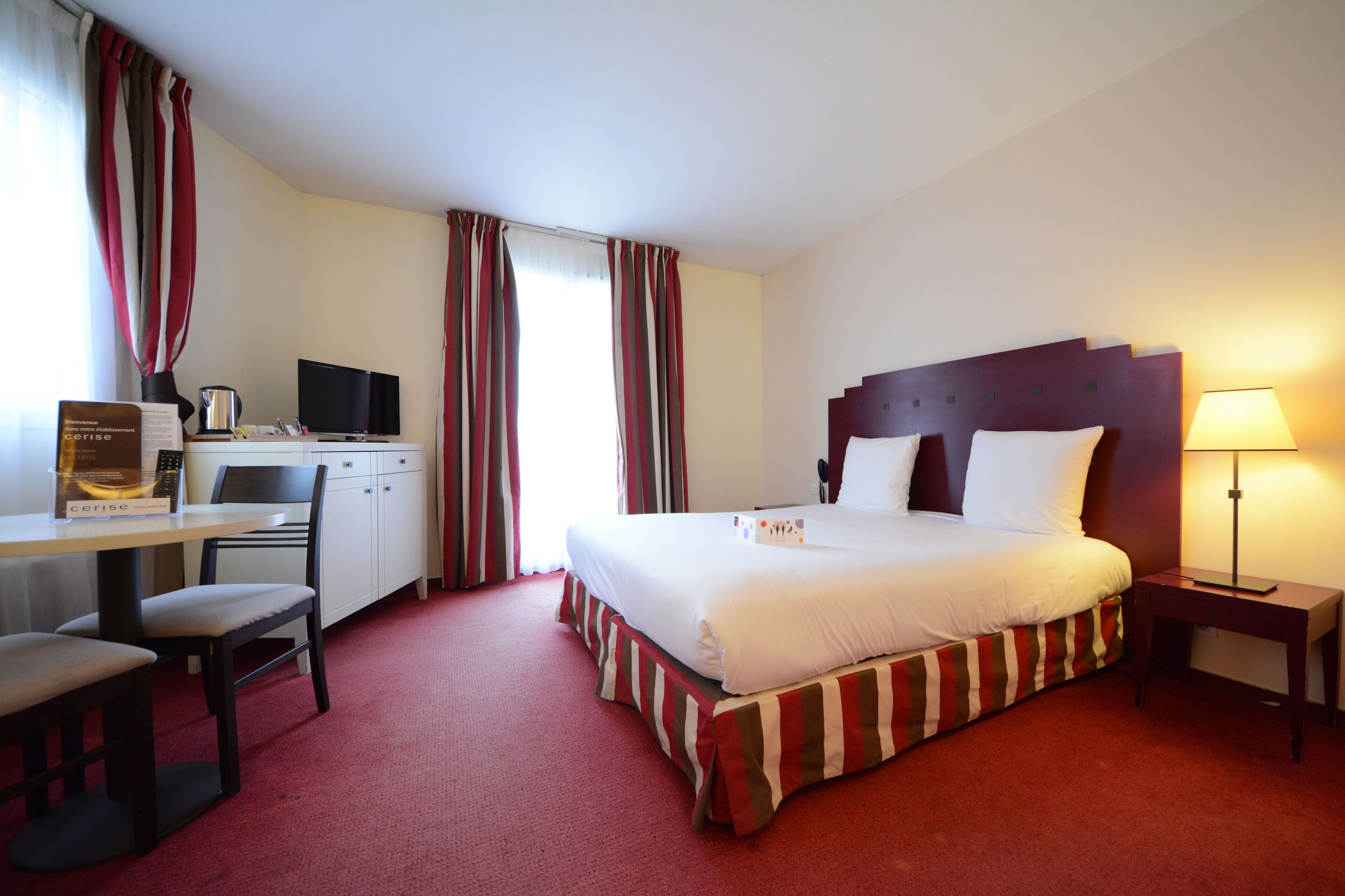 Une chambre d’hôtel avec un lit, un bureau, une chaise et une lampe.
